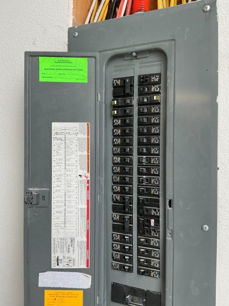 Electrical panel with multiple circuit breakers and labels on the side.