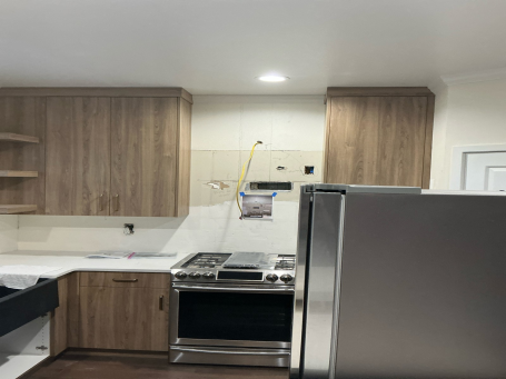 Modern kitchen featuring wooden cabinets, stainless steel appliances, and a white countertop.
