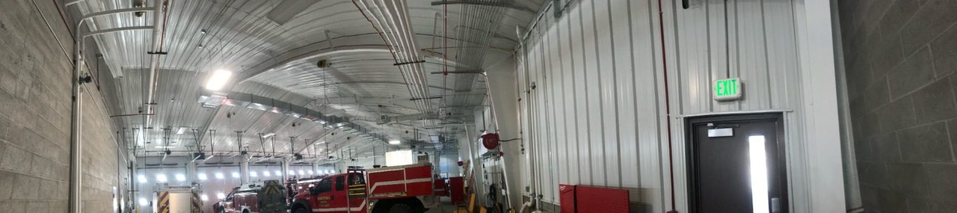 Interior of a spacious industrial building with concrete walls and overhead lighting.