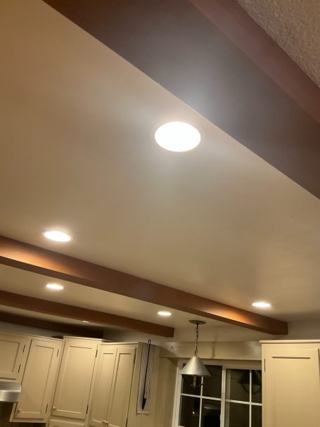 Ceiling featuring recessed lights and wooden beams in a kitchen setting.