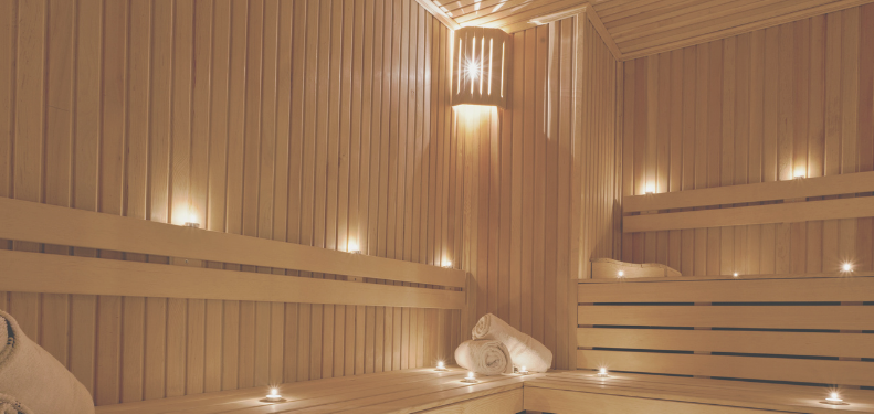 Warm, wooden sauna interior with flickering candles and soft towels.